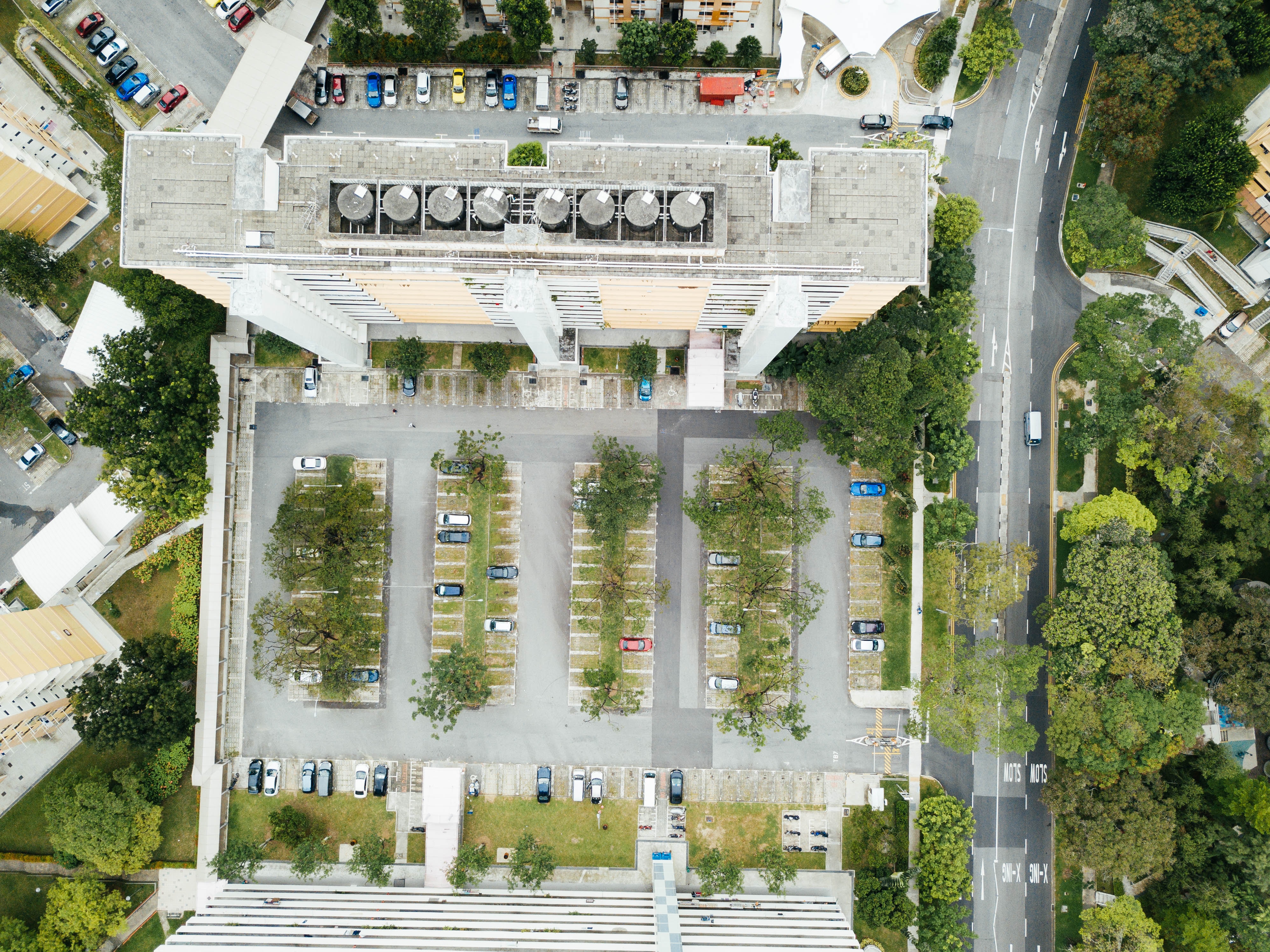 building with a concrete parking lot with trees from a bird's eye view